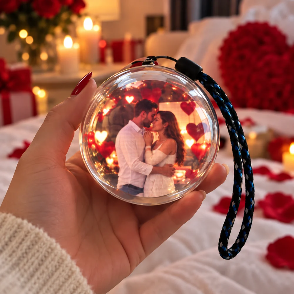 Hand holding a sphere showing a couple embracing beside roses and candles